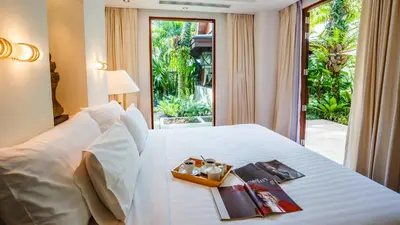a hotel room with a white bed with a window at Villa in the Garden, Surin Beach with private spa. in Surin Beach