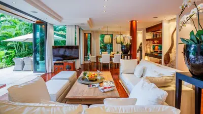 a living room with white couches and a table at Villa in the Garden, Surin Beach with private spa. in Surin Beach