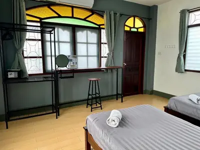 a bedroom with two beds and a bar with windows at Niece Hostel Phuket - Bangtao Beach in Ban Thalat Choeng Thale