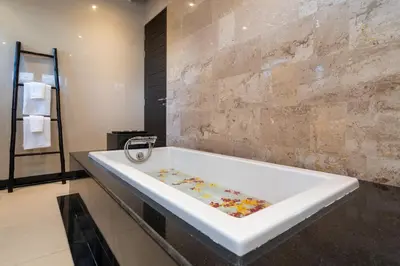 a bath tub in a bathroom with a stone wall at The Harmony Pool Villa Phuket in Bang Tao Beach