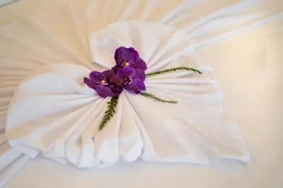 a purple flower on top of a white dress at The Harmony Pool Villa Phuket in Bang Tao Beach