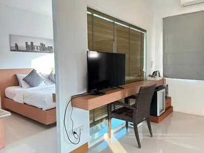 a bedroom with a desk with a television and a bed at Clear House Resort - SHA Extra Plus in Kamala Beach