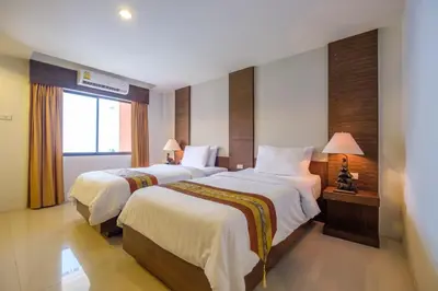 a hotel room with two beds and a window at Naina Resort & Spa - SHA Extra Plus in Patong Beach