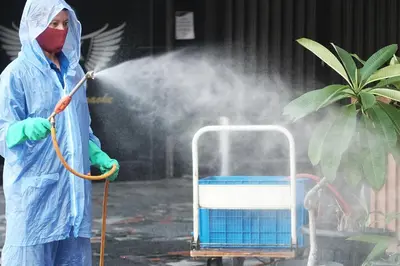 a person in a raincoat andmask spraying a water fountain at Rawai Paradise in Rawai Beach