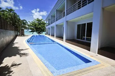 a swimming pool in front of a building at Chalong Beach Front Residence in Rawai Beach