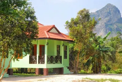 a green house with a red roof and trees at Anacar Bungalows in Krabi town