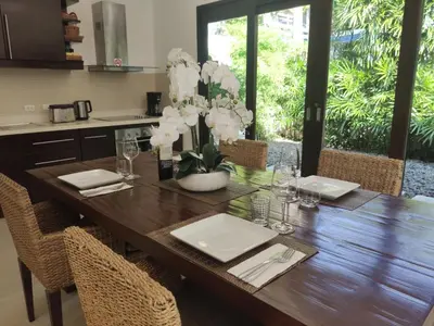 a dining room table with white flowers in a vase at Villa Suksan - Kubu in Nai Harn Beach