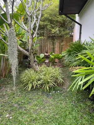a fire hydrant in a garden next to a tree at Villa Suksan - Kubu in Nai Harn Beach
