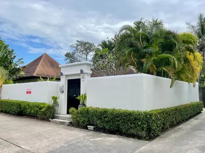 a white fence in front of a house with palm trees at Villa Suksan - Kubu in Nai Harn Beach
