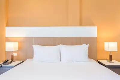 a large bed with two white pillows and two lamps at Chanalai Hillside Resort, Karon Beach in Karon Beach