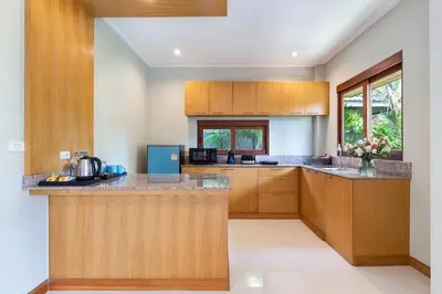 a kitchen with wooden cabinets and a counter top at Lady Naya Villas - SHA Extra Plus in Rawai Beach