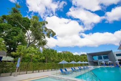 a pool with chairs and umbrellas in front of a building at Seabed Grand Hotel Phuket in Phuket Town
