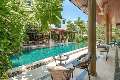 a pool at a resort with chairs and tables at Coco Paradiso Phuket SHA in Phuket Town