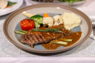 a plate of food with meat and vegetables on a table at Coco Paradiso Phuket SHA in Phuket Town