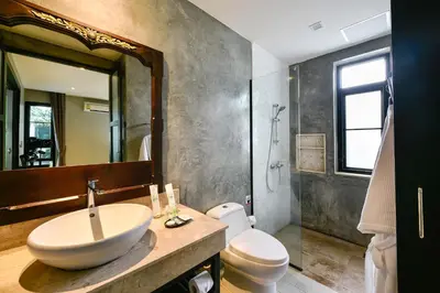 a bathroom with a sink and a toilet and a mirror at Coco Paradiso Phuket SHA in Phuket Town