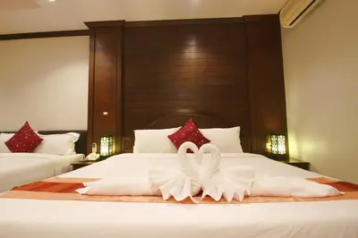 two white swans are sitting on a bed at Baan Veerakit Hotel in Patong Beach