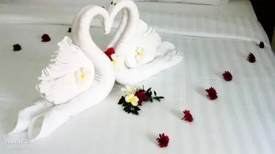 two swans made out of flowers on a bed at G-HAN Residence in Nai Yang Beach