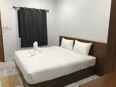 a bedroom with a white bed with a black curtain at G-HAN Residence in Nai Yang Beach