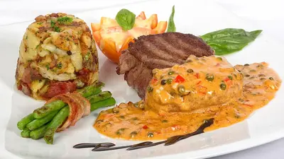 a white plate of food with meat and vegetables at Austrian Garden Hotel & Restaurant Patong in Patong Beach
