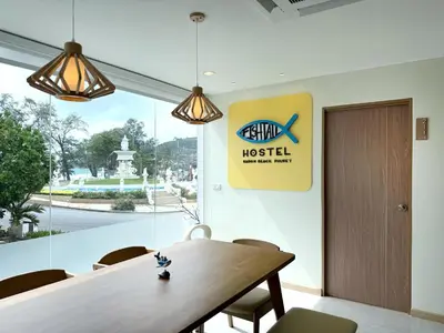 a dining room with a wooden table and a sign at Fishtail Hostel Phuket in Karon Beach