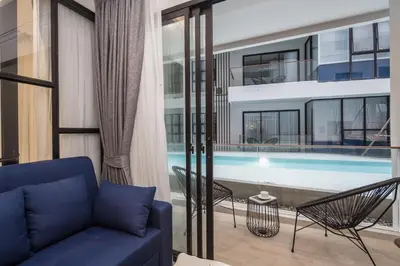a living room with a couch and a swimming pool at Palmyrah Surin Beach Residence in Surin Beach