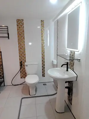 a white bathroom with a toilet and a sink at Living Room Guesthouse & Cafe Bar in Karon Beach