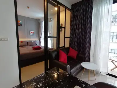 a living room with a black leather chair and a mirror at Palmyrah Surin Beach By Risa in Surin Beach