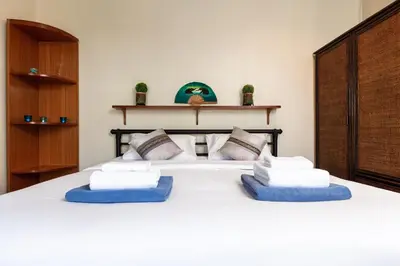 a bedroom with a white bed with blue pillows at Sabai Villa Kata by RESAVA in Kata Beach