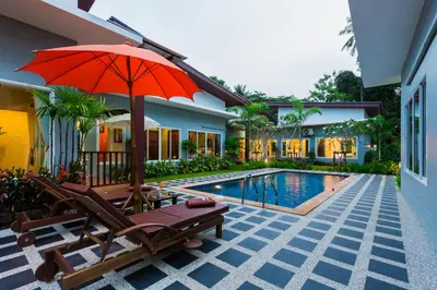 a patio with chairs and an umbrella and a swimming pool at Irawan House in Ao Nang Beach