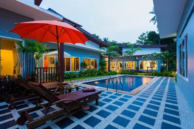 an umbrella and chairs next to a swimming pool at Irawan House in Ao Nang Beach