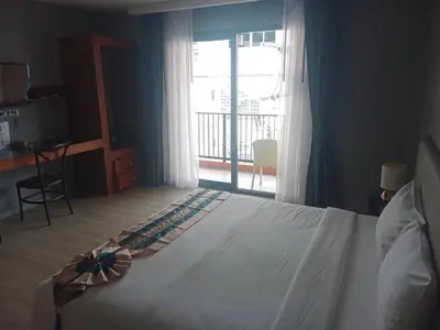 a bedroom with a large bed and a balcony at Aonang Inn in Krabi town