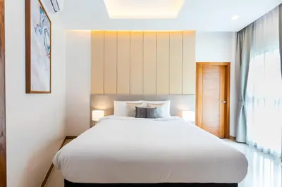 a bedroom with a large white bed and a window at Palmetto Condominium in Karon Beach