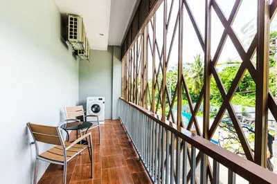 a balcony with a table and chairs and a window at Palmetto Condominium in Karon Beach