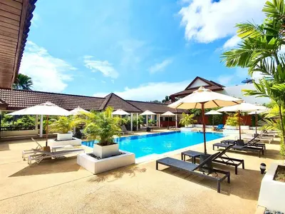 a swimming pool with chairs and umbrellas and a resort at The Sands 3 Bedrooms Beachside Apartment in Naiharn in Nai Harn Beach