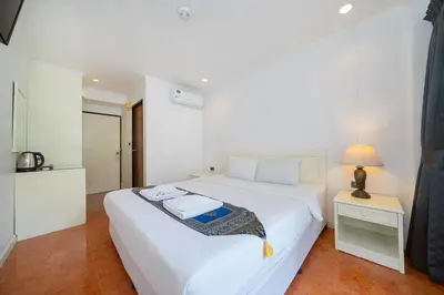 a white bedroom with a white bed and a lamp at Patong Central Residence and Apartment in Patong Beach