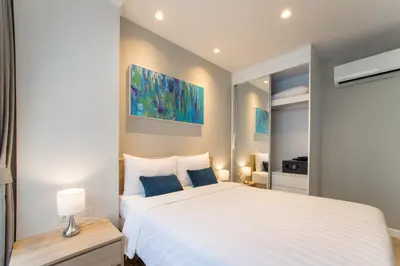 a bedroom with a large white bed with blue pillows at 1bdr Pool Access Apartment Bangtao #5103 in Bang Tao Beach