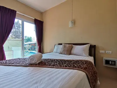 a bedroom with a large bed with a window at Serene Villa Phuket in Chalong