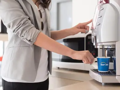 a woman is using a coffee machine at HOP INN Phuket Old Town in Phuket Town