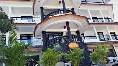 a building with a building with palm trees in front of it at La Capannina Hotel Patong in Patong Beach