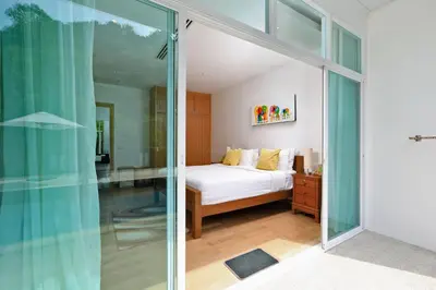 a bedroom with a bed and a sliding glass door at Suite Cascade 2BR Family Deluxe Kamala Falls in Kamala Beach