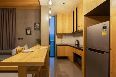 a kitchen and dining room with a wooden table at Sara's Nest - Top Floor Seaview apartments in Nai Harn Beach