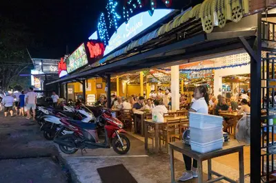 a group of people sitting outside a restaurant at night at NaiHarn Sea Condo, Top floor, Mountain View in Nai Harn Beach