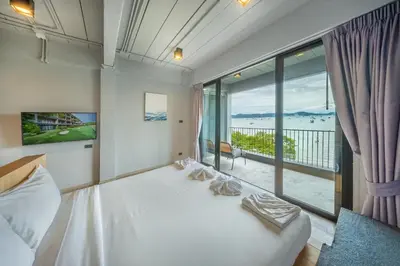 a bedroom with a white bed and a large window at SHIN Arch39 Phuket Beach Front - SHA Plus in Chalong
