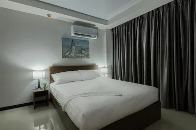 a bedroom with a bed and a window with avertisement at NaiHarn Pearl Condo - Pets Friendly! in Nai Harn Beach