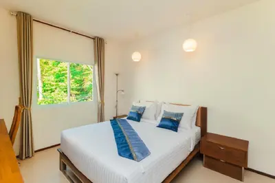 a bedroom with a large white bed with blue pillows at Genesis Villas in Rawai Beach