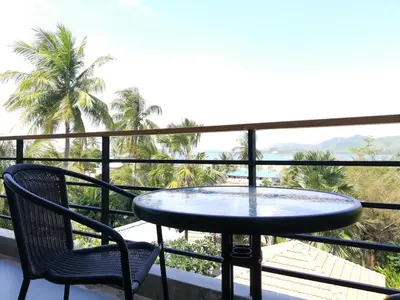 a table and chairs on a balcony with palm trees at Laemsai Resort in Thalang