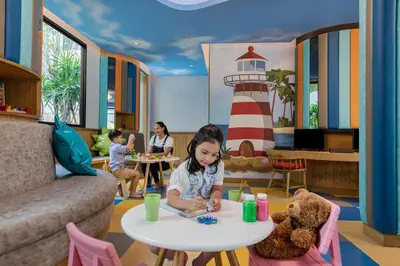 a little girl sitting at a table in a room with a lighthouse at Four Points by Sheraton Phuket Patong Beach Resort in Patong Beach