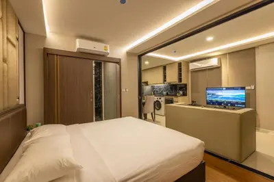 a bedroom with a large white bed and a television at Sea View Panora Surin by Holy Cow, 1-BR in Surin Beach