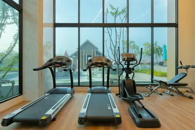 a gym with treadmills and ellipticals in front of a window at Sea View Panora Surin by Holy Cow, 1-BR in Surin Beach