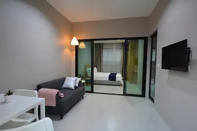 a living room with a couch and a bedroom at The Grey House Palai Phuket in Chalong